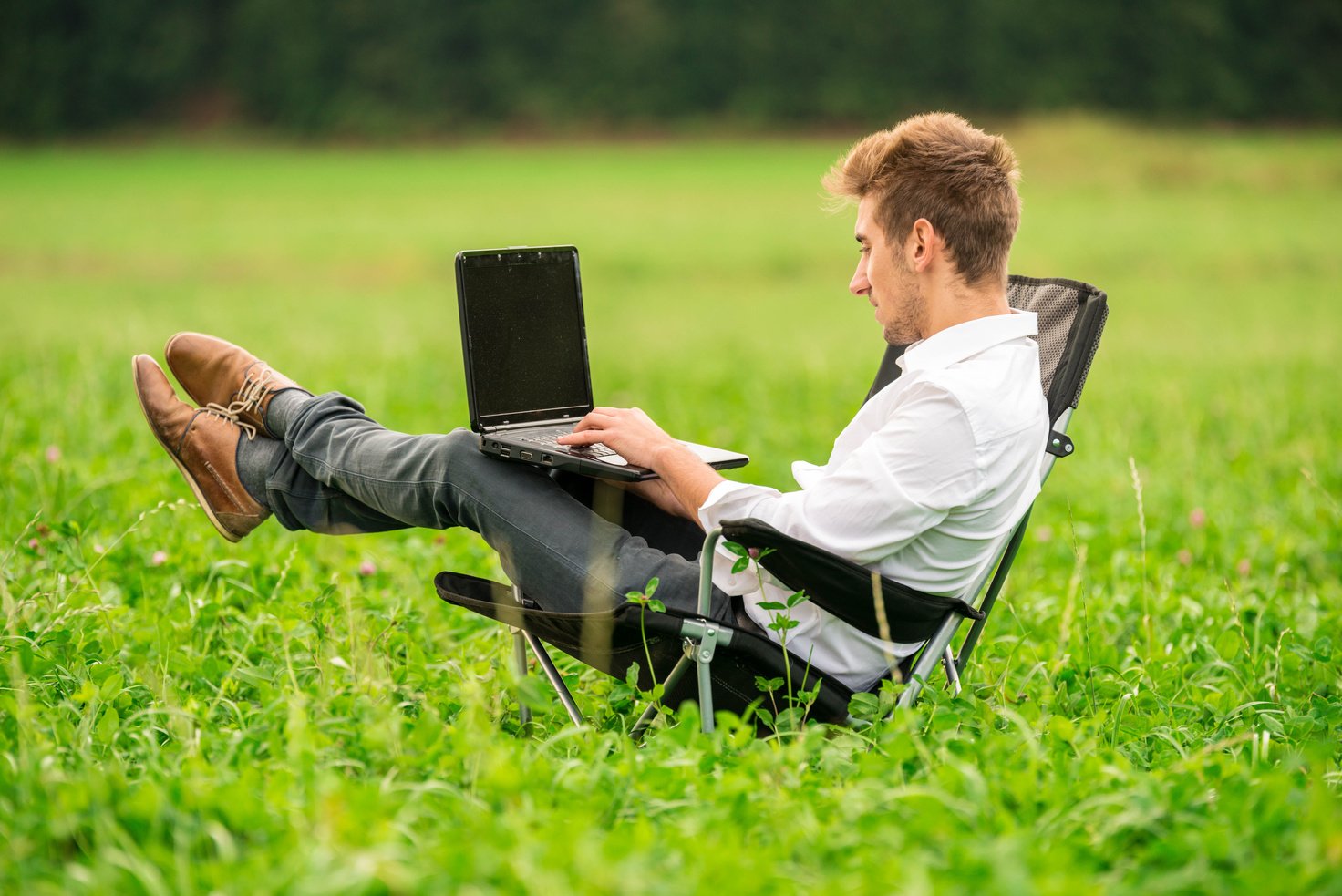 Businessman working on his laptop outside in nature